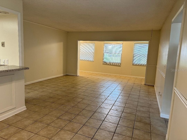 unfurnished room with tile floors and a textured ceiling