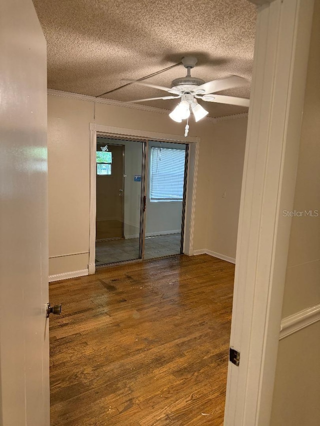 empty room with a textured ceiling, dark hardwood / wood-style floors, and ceiling fan