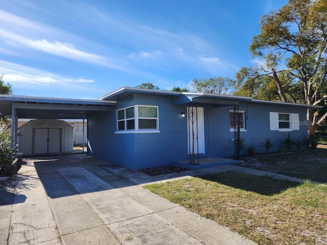 ranch-style house featuring a storage unit and a carport