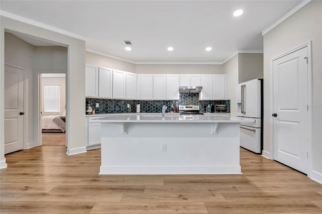 kitchen with high end white fridge, a center island with sink, light hardwood / wood-style floors, and stainless steel electric stove