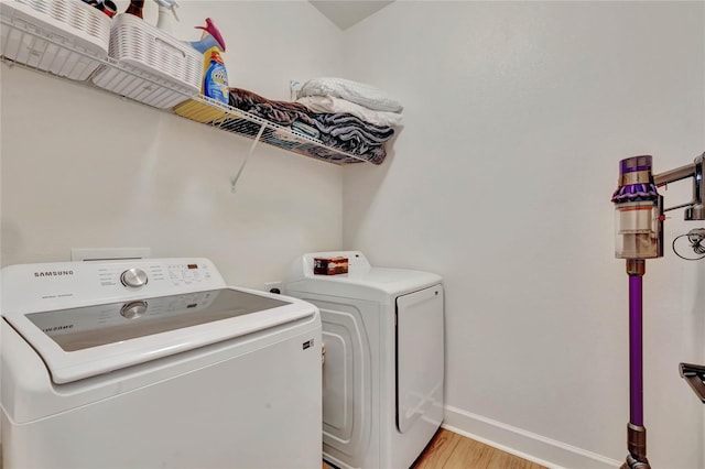 laundry area with light hardwood / wood-style floors and washing machine and clothes dryer