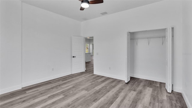 unfurnished bedroom with ceiling fan, wood-type flooring, and a closet