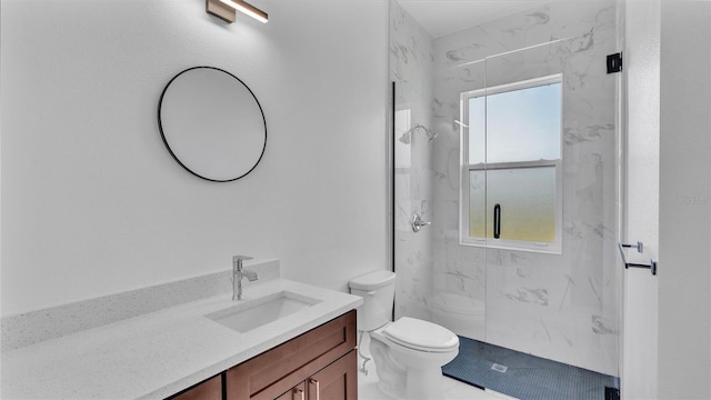 bathroom featuring vanity, toilet, and a tile shower