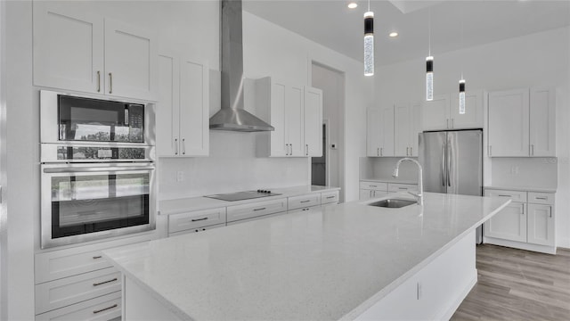 kitchen with light hardwood / wood-style flooring, black appliances, wall chimney range hood, sink, and an island with sink