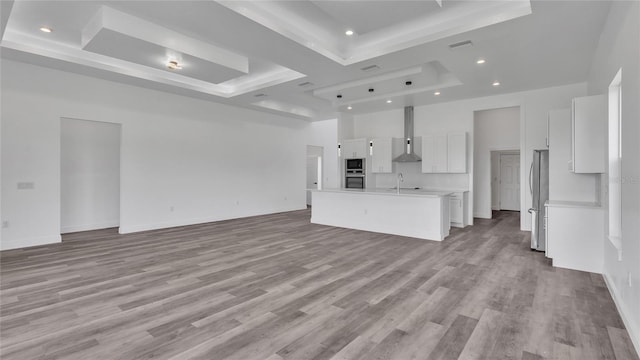 unfurnished living room featuring light hardwood / wood-style floors, sink, and a tray ceiling