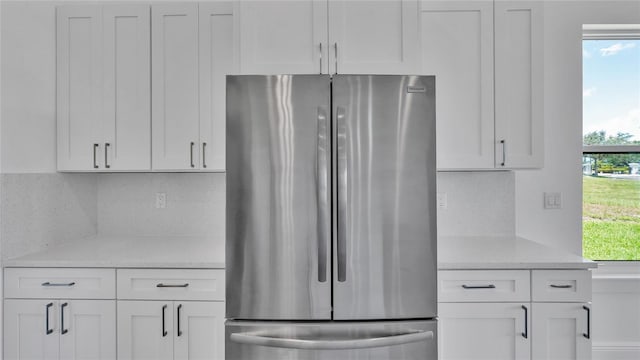 kitchen with stainless steel fridge, a wealth of natural light, white cabinets, and backsplash