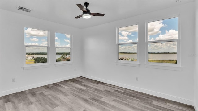 empty room featuring a healthy amount of sunlight, hardwood / wood-style floors, and ceiling fan