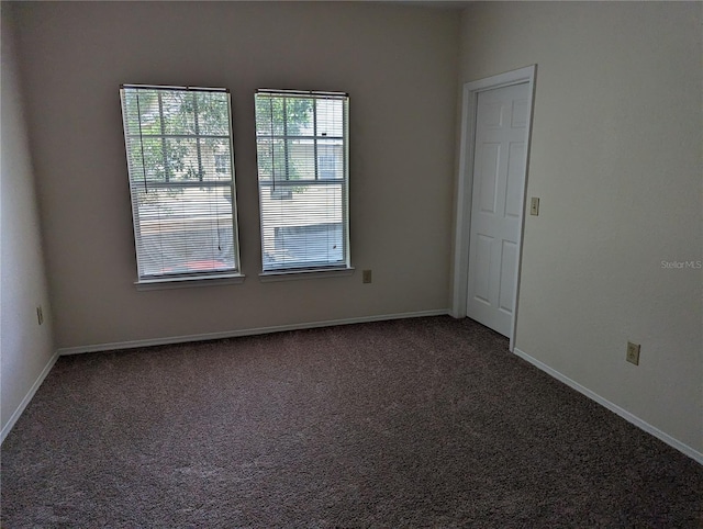 spare room with dark carpet