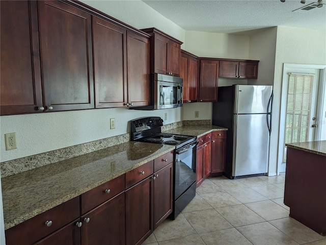 kitchen with dark stone countertops, light tile patterned flooring, a textured ceiling, and appliances with stainless steel finishes