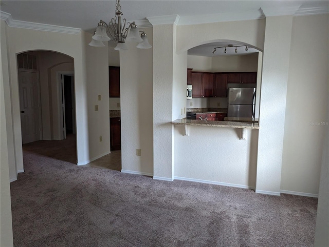 kitchen featuring kitchen peninsula, appliances with stainless steel finishes, dark carpet, ornamental molding, and hanging light fixtures