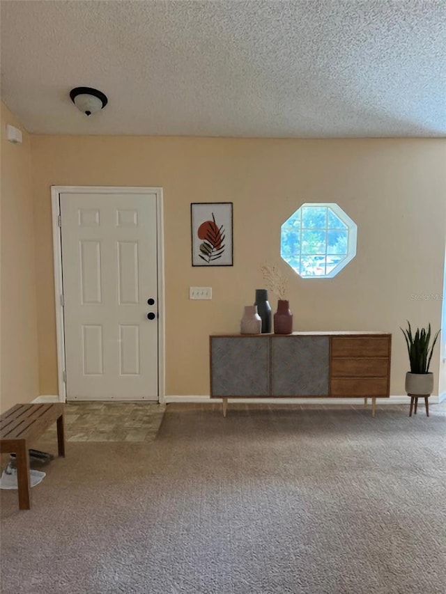 carpeted foyer with a textured ceiling