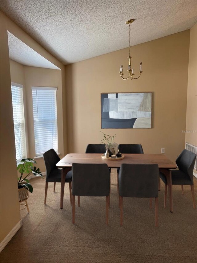 carpeted dining area featuring a notable chandelier and a textured ceiling