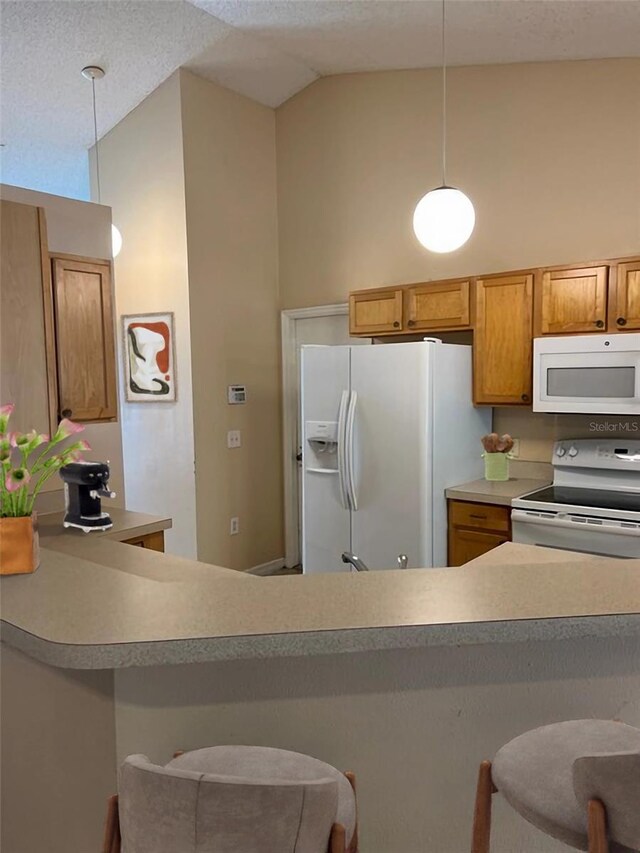 kitchen with white appliances, high vaulted ceiling, a kitchen bar, and pendant lighting