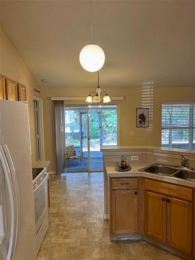 kitchen featuring white appliances, hanging light fixtures, an inviting chandelier, and sink