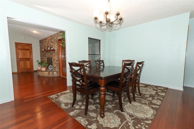 dining area featuring a textured ceiling, lofted ceiling, dark wood-type flooring, and an inviting chandelier