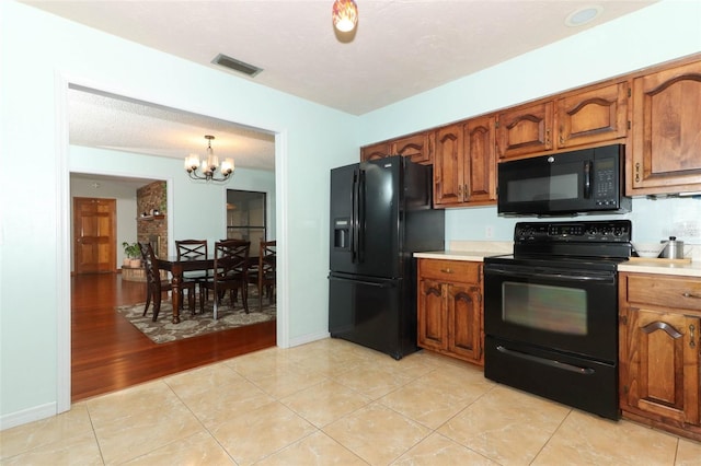 kitchen with black appliances, a notable chandelier, light hardwood / wood-style floors, and decorative light fixtures