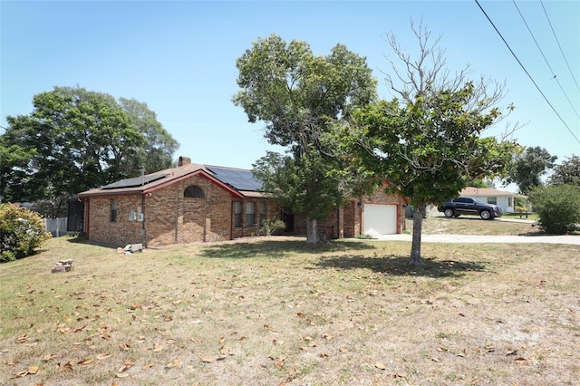 view of front of property featuring a garage, a front yard, and solar panels