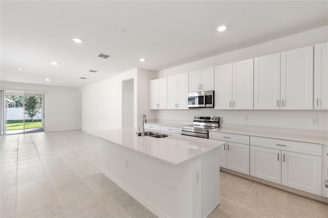 kitchen with appliances with stainless steel finishes, a kitchen island with sink, sink, and white cabinets