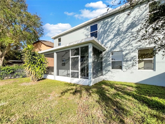 rear view of property with a sunroom and a yard