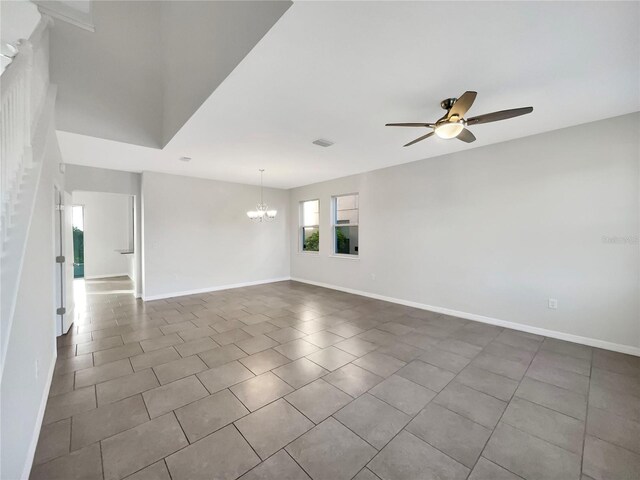 spare room featuring dark tile patterned flooring and ceiling fan with notable chandelier