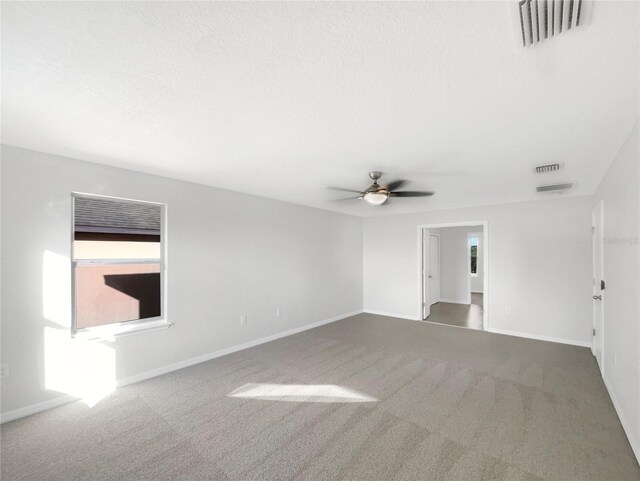 carpeted empty room with ceiling fan and a textured ceiling