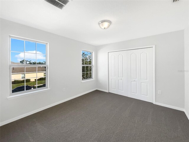 unfurnished bedroom featuring dark colored carpet and a closet