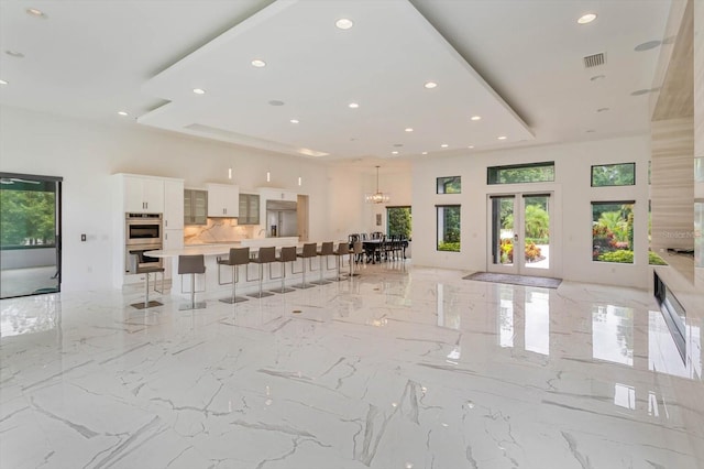 unfurnished living room featuring a chandelier, french doors, and light tile floors