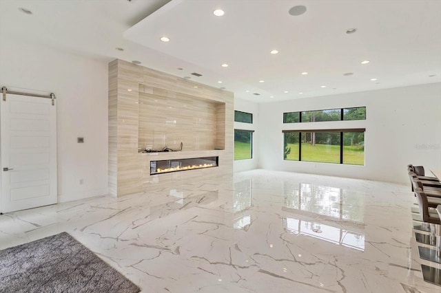 unfurnished living room featuring tile floors, a barn door, a tile fireplace, and tile walls