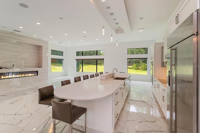 kitchen with a healthy amount of sunlight, high end refrigerator, and white cabinets