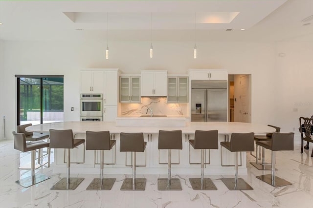 kitchen featuring a kitchen breakfast bar, stainless steel appliances, a large island, backsplash, and sink