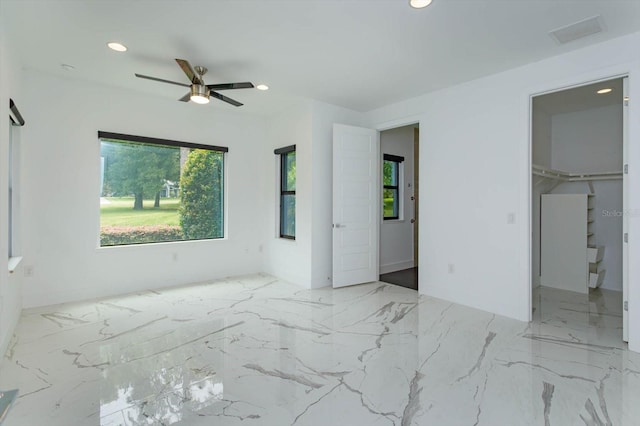 unfurnished bedroom with a spacious closet, a closet, ceiling fan, and light tile floors