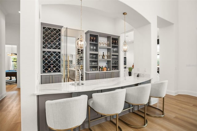 bar with sink, billiards, pendant lighting, vaulted ceiling, and hardwood / wood-style flooring