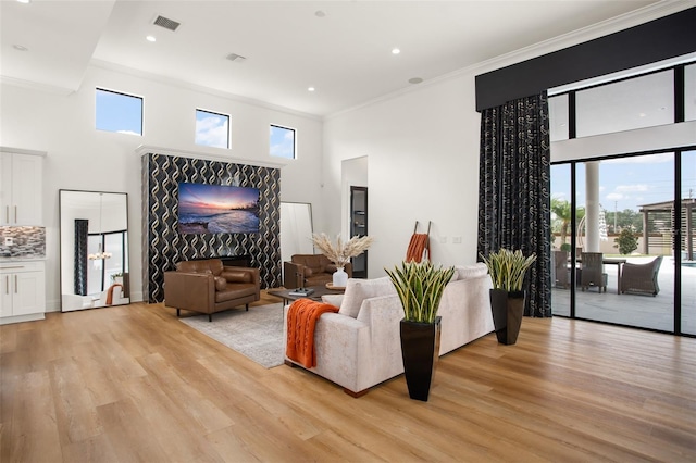 living room with a healthy amount of sunlight, light wood-type flooring, and a high ceiling