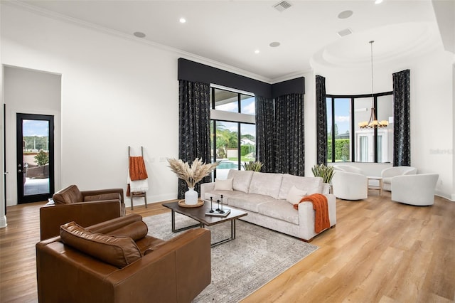 living room featuring ornamental molding, light hardwood / wood-style floors, a wealth of natural light, and a notable chandelier