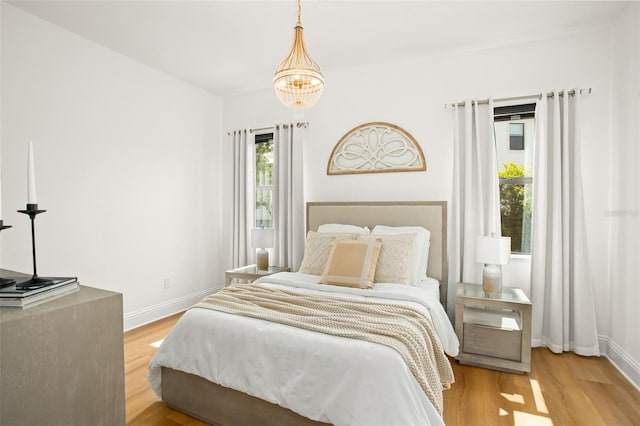 bedroom with light wood-type flooring and an inviting chandelier