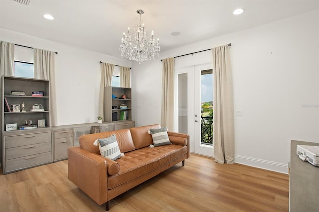 living area with a notable chandelier, french doors, and light hardwood / wood-style flooring