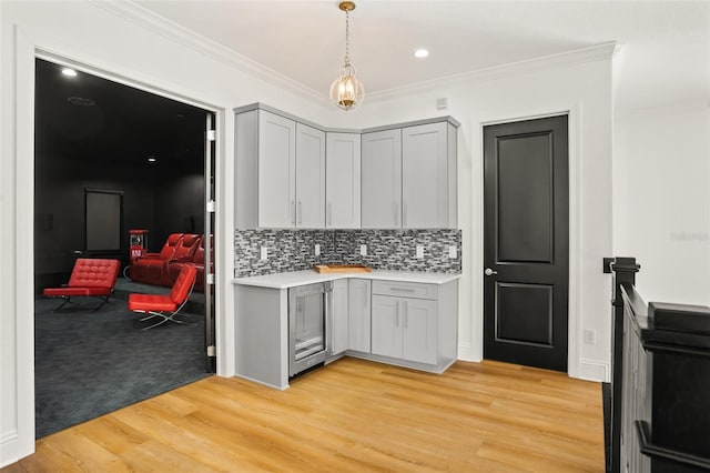 kitchen featuring gray cabinetry, light hardwood / wood-style floors, crown molding, and tasteful backsplash