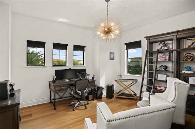 home office with a notable chandelier, plenty of natural light, and light wood-type flooring