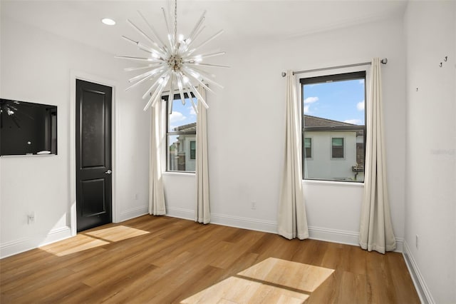 spare room with light hardwood / wood-style flooring and a notable chandelier