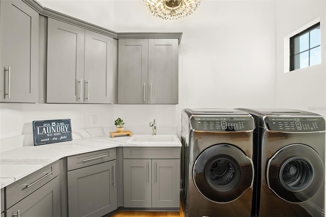 laundry area featuring sink, cabinets, an inviting chandelier, separate washer and dryer, and light hardwood / wood-style floors