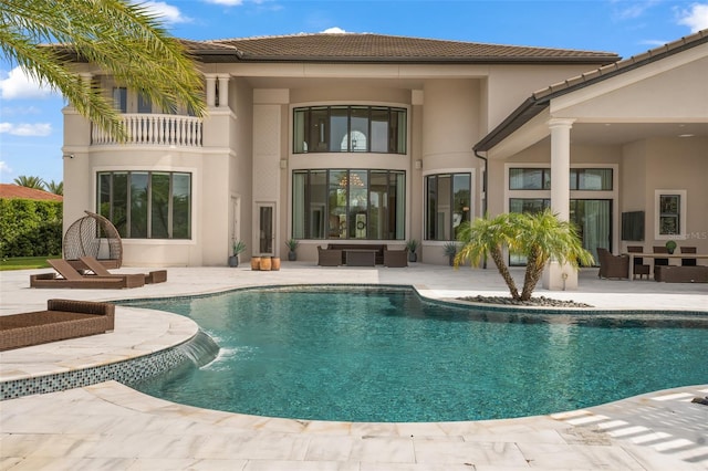 rear view of property with a patio area, pool water feature, a balcony, and an outdoor hangout area