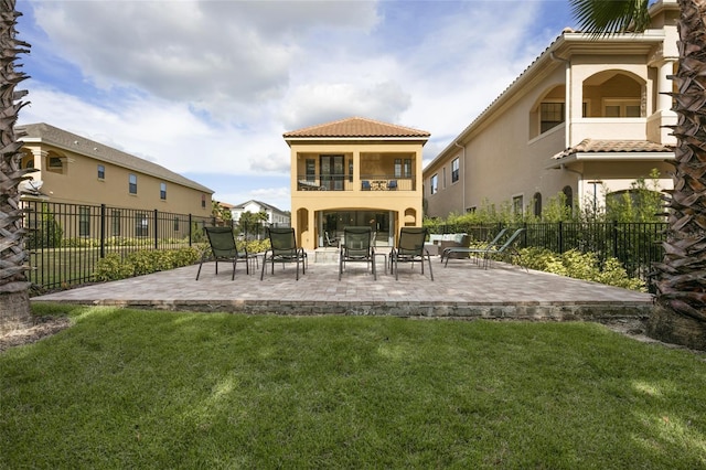 rear view of house with a yard, a balcony, and a patio area