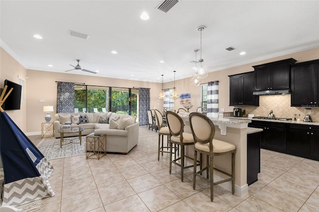 kitchen featuring hanging light fixtures, plenty of natural light, a kitchen bar, and backsplash