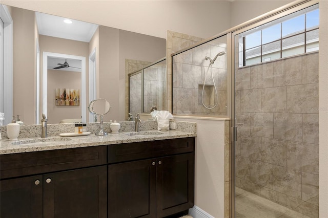 bathroom featuring ceiling fan, vanity with extensive cabinet space, a shower with shower door, and double sink