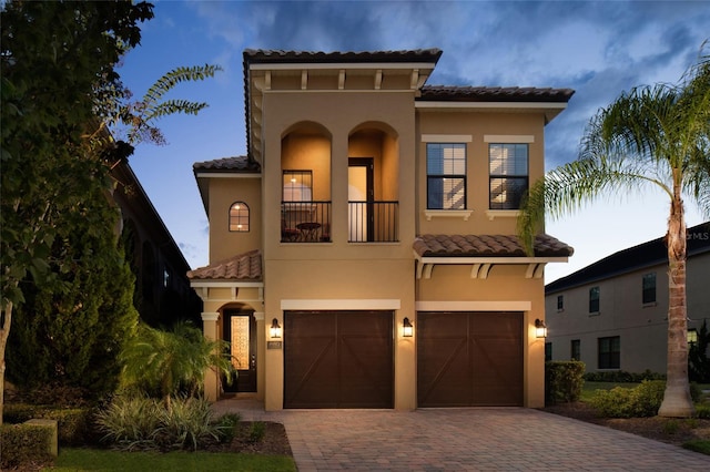 mediterranean / spanish-style home featuring a garage and a balcony