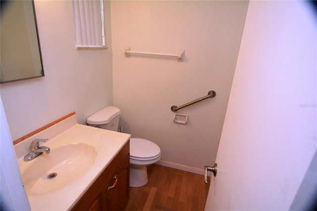 bathroom featuring hardwood / wood-style flooring, toilet, and vanity with extensive cabinet space