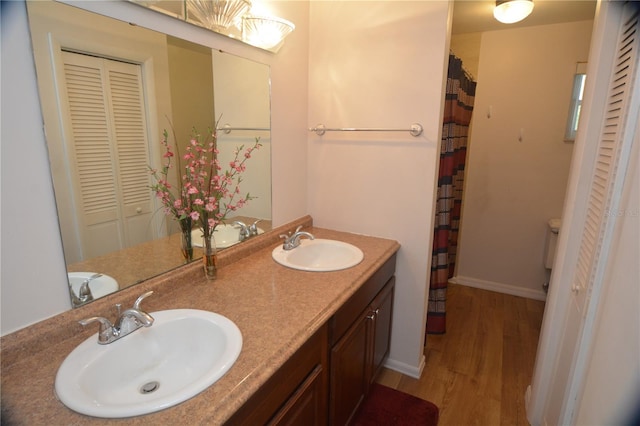 bathroom featuring hardwood / wood-style flooring, toilet, double sink, and oversized vanity