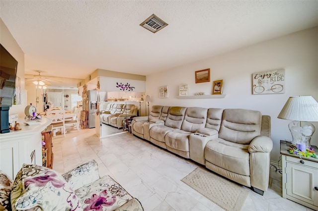 living room with a textured ceiling and ceiling fan