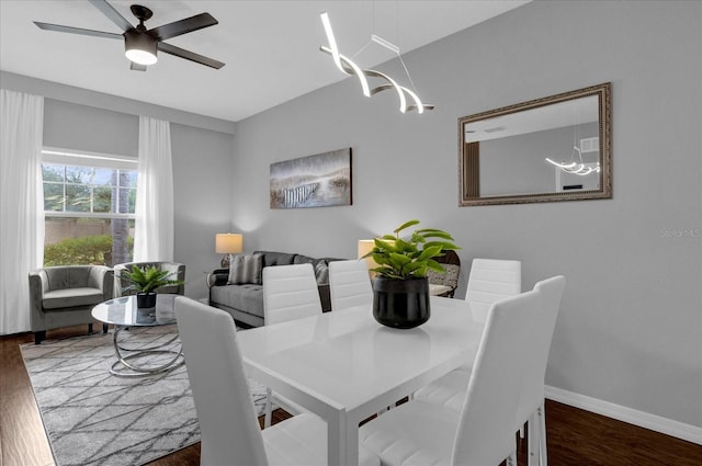 dining room with dark hardwood / wood-style floors and ceiling fan with notable chandelier