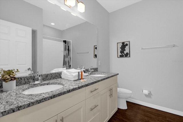 bathroom featuring hardwood / wood-style flooring, double sink, toilet, and vanity with extensive cabinet space